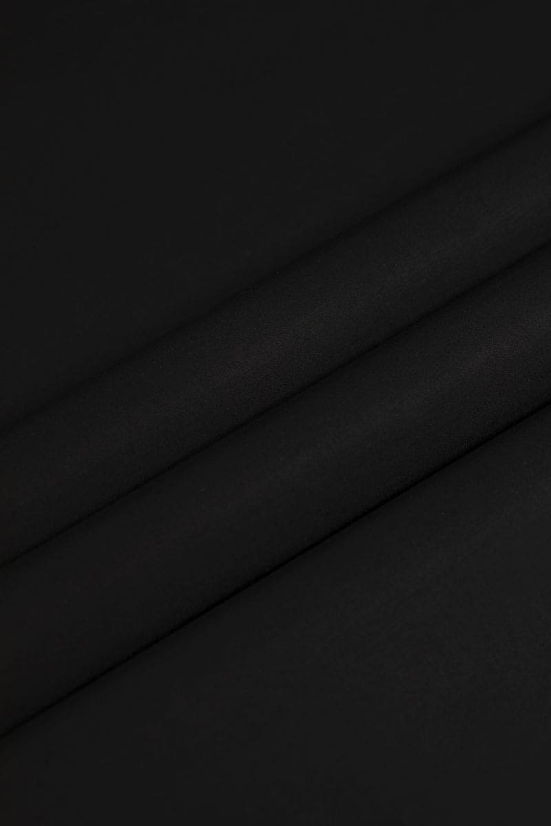 Istanbul Noir fabric by SGF — close-up flat lay texture of deep black premium unstitched fabric with subtle shine, men’s luxury fabric Pakistan.