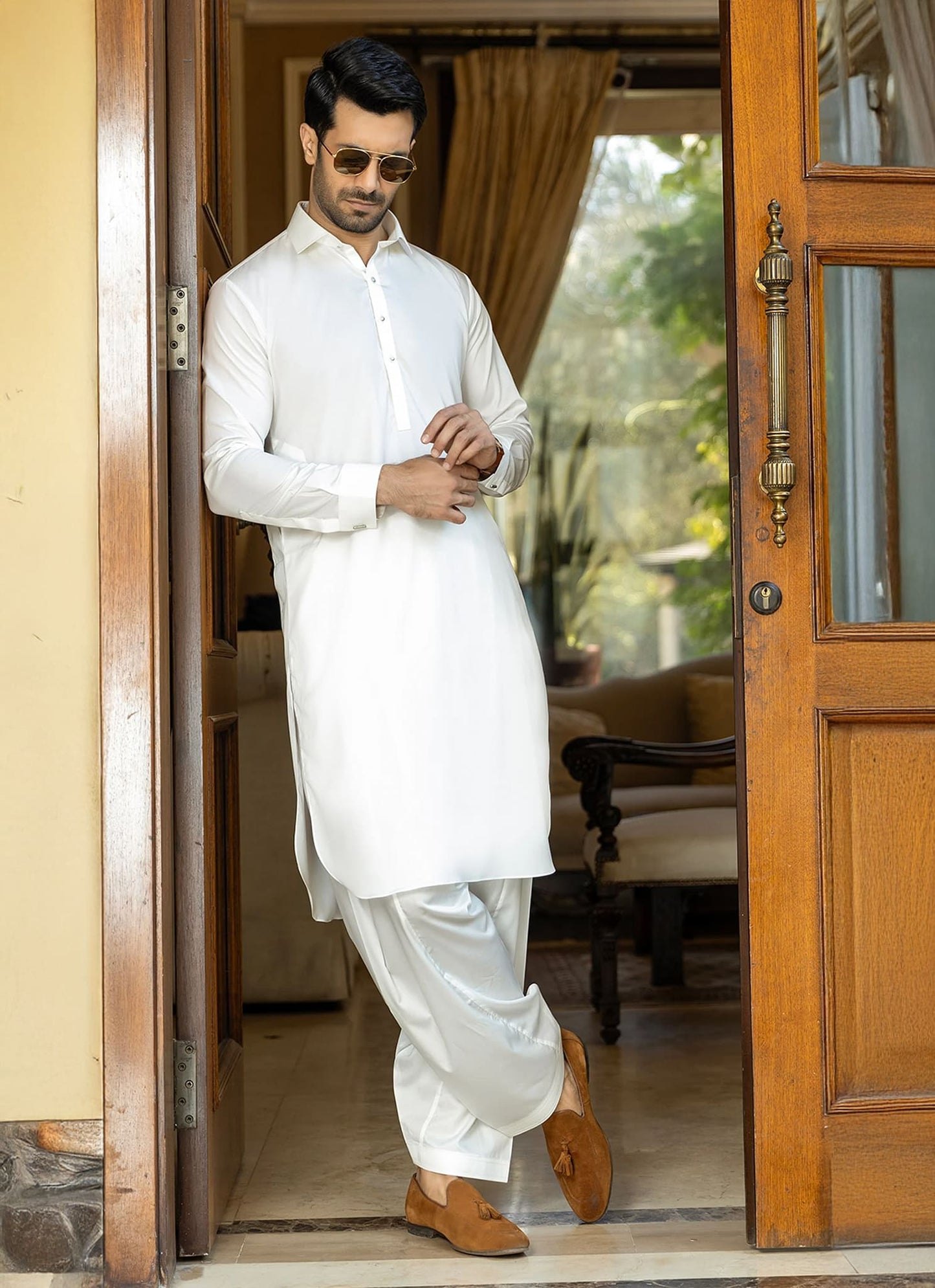 Man in a white traditional outfit standing in a doorway.
Sheikh Gulzar Fabrics Viven — premium self-check white fabric styled on model, wrinkle-free luxury men’s shalwar kameez fabric Pakistan.